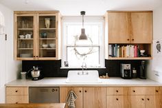 a kitchen with wooden cabinets and a white sink under a window next to a book shelf