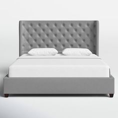 an upholstered bed with white pillows and gray headboard is shown in front of a plain background