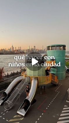 an outdoor play area with slides and water slide in front of the cityscape