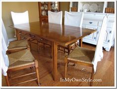 a dining room table with chairs around it and white linens on the chair backs