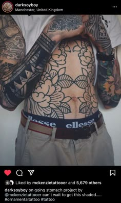 a man with many tattoos on his body and hands behind his back is holding something in front of him