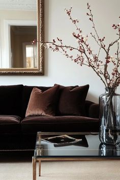 a living room with a couch, coffee table and mirror on the wall in front of it