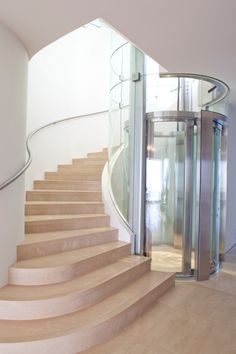 there is a spiral staircase with glass doors on the side and wooden steps to the second floor