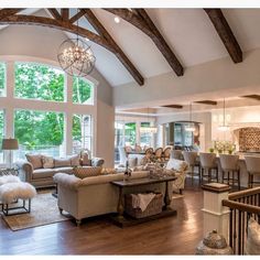 a living room filled with furniture next to a large open floor plan and high ceilings