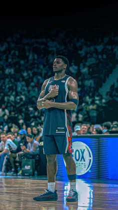 a man standing on top of a basketball court in front of an arena filled with people