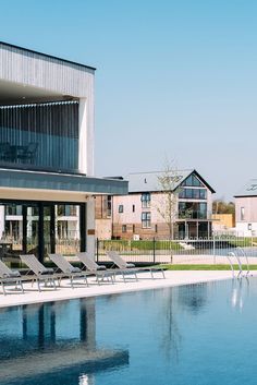 an empty swimming pool with lounge chairs in front of it and two buildings on the other side