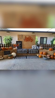 pumpkins and hay bales on display in front of a store with black and white checkered table cloth