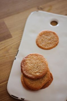 three cookies sitting on top of a white tray next to a wooden table with one cookie in the middle