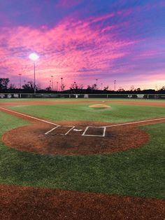 a baseball field with the sun setting behind it