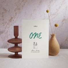 there is a card with the word one on it next to two vases and a candle holder