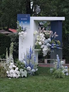 flowers are growing out of the side of a white structure with blue writing on it