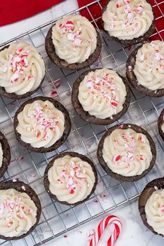 chocolate cookies with white frosting and candy canes on a cooling rack