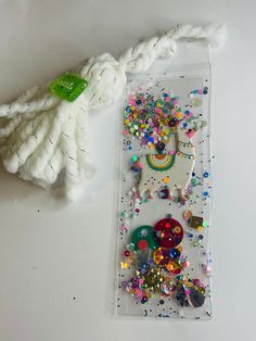 an assortment of buttons and sequins on a plastic case next to a tassel