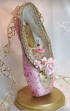 a pink shoe with gold trim and flowers on it sitting on a table next to a chain