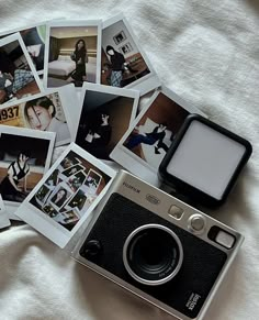 an old camera and some polaroid pictures on a bed