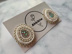 a pair of white and gold beaded earrings on top of a card with the words anikiw