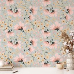 a white table topped with a vase filled with flowers next to a pink wallpaper