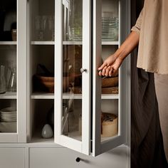 a person is opening the glass door of a cabinet