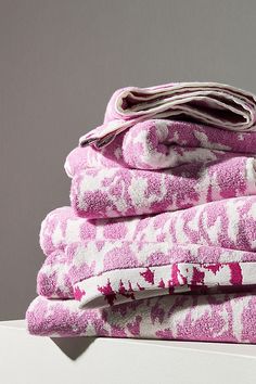 a stack of pink towels sitting on top of a white shelf next to a gray wall