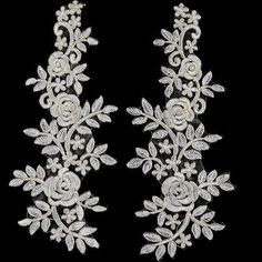 two white flowers and leaves are attached to the back of a pair of brooches