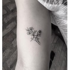 a black and white photo of a flower tattoo on the left arm, with an arrow in the middle