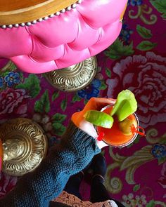 a person holding a drink with fruit on the table next to other foods and decorations