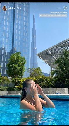 a woman in a swimming pool with the burj building in the back ground