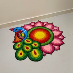 a colorfully painted peacock sitting on top of a white floor next to a flower