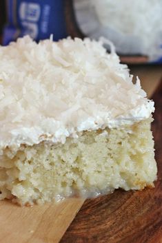 a piece of coconut cake sitting on top of a wooden cutting board