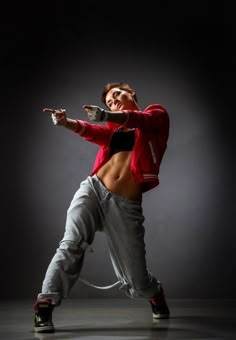 a man in red shirt and grey pants doing a dance move with his arms out