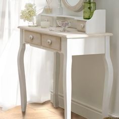 a white table with a mirror and vase on it