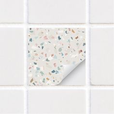 a white tiled wall with multicolored confetti tiles on the bottom half