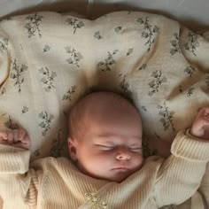 a baby is sleeping on a blanket with its eyes closed and hands in the air