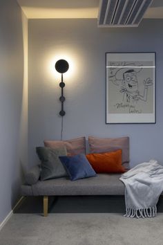 a living room with a gray couch and some pillows on the floor next to a lamp