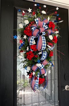 a patriotic wreath with red, white and blue flowers on the front door for memorial day