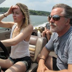 a man driving a boat with a woman on the front seat and another person sitting in the driver's seat