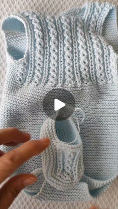 someone crocheting the bottom of a knitted sweater