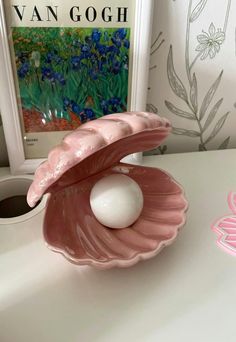 a pink shell with an egg in it sitting on a table next to a vase