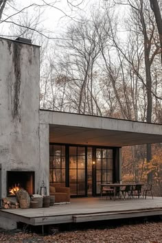 a concrete house in the woods with a fire place and patio area on one side