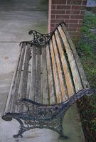 an old wooden bench sitting on the sidewalk