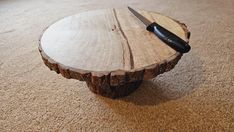 a knife sits on top of a piece of wood that is sitting on the floor