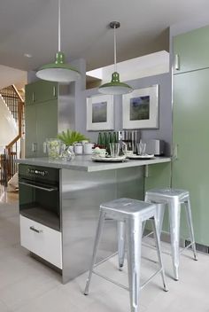 two stools sit in front of an island with green walls and white tile flooring