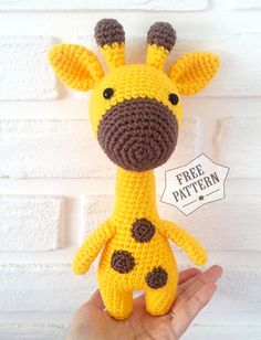 a crocheted giraffe stuffed animal in the palm of someone's hand