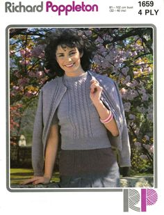 a woman wearing a gray sweater and black pants in front of a tree with purple flowers