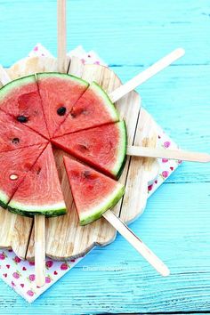 slices of watermelon sitting on top of wooden sticks