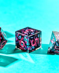 three colorful dices sitting on top of a blue surface with shadows coming from them