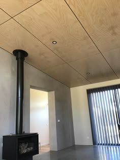 an empty room with a wood stove in the center and sliding glass doors behind it