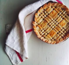 a pie sitting on top of a white table next to a napkin and spoons