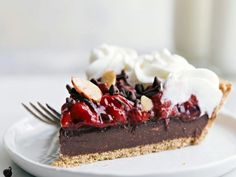 a slice of chocolate pie with whipped cream and cherries on top, sitting on a white plate