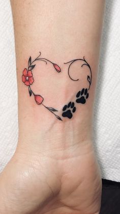 a heart shaped tattoo with paw prints and flowers on the side of the ankle area